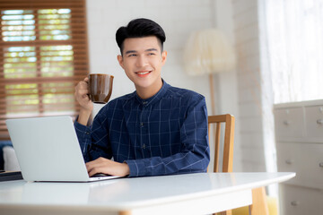 Fototapeta premium Young business man working from home with laptop computer on desk, freelance male sitting stay home using notebook for communication and relax on table, entrepreneur in startup business, new normal.