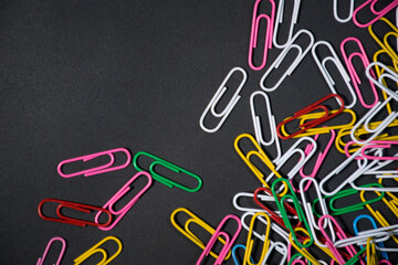 Coloured paperclips on black background for use alone or as a design element and design resources