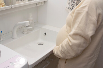 A young pregnant Asian woman washing hands at bathroom