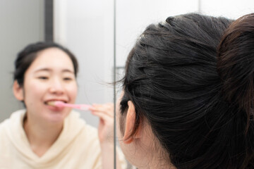 A young pregnant Asian woman brushing her teeth