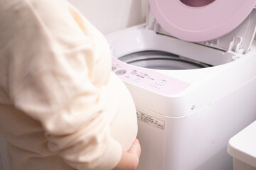 A young pregnant Asian woman doing the laundry