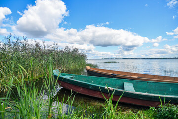 Obraz premium Wooden fishing boat on the lake with transparent blue sky and clear water