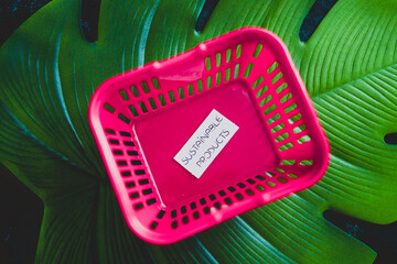 sustainable products and consumer behaviour, empty pink shopping basket with text on top of...