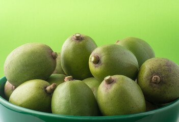 ambarella or june plum curry, edible fruit in a bowl, closeup view taken on a light green background