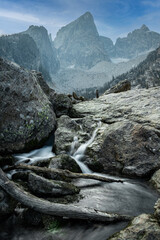 View of a waterfall in front Delta Lake in Grand Teton National Park, Wyoming during the summer with a blue sky and clouds.