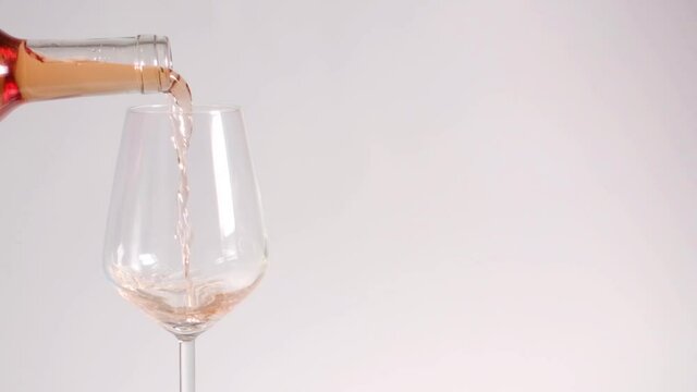 Slow-motion pouring rose wine on white background