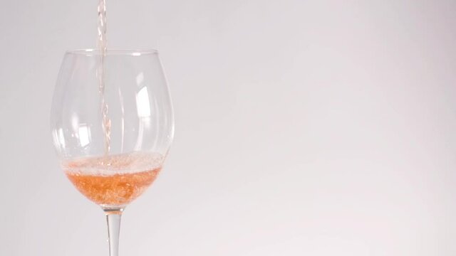 Slow-motion pouring rose wine on white background