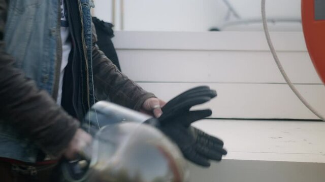 a person getting the motorcycle equipment, the silver grey motorcycle helmet, the black leather motorcycle gloves
