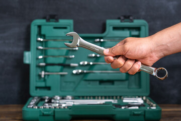 Car mechanic's hand with a wrench on the background of an open box with a tool