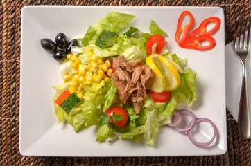 Tasty tuna salad with lettuce, fresh vegetables, tomatoes and corn. Healthy Green salad with tuna, corn and beans