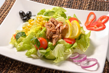 Tasty tuna salad with lettuce, fresh vegetables, tomatoes and corn. Healthy Green salad with tuna, corn and beans