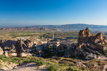 トルコ　カッパドキアのウチヒサール城から見える奇岩群と洞窟住居とギョレメ国立公園の空を飛ぶ熱気球