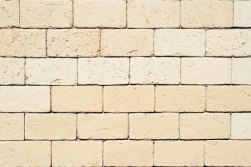 Rough decorative light yellow large brick, textured stone wall outdoors background. Structural beige material for exterior wall decoration