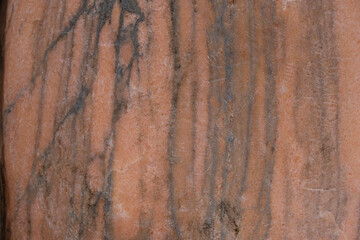 Pale coral color stone with black streaks background. Copy space.