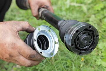 Wheel driveshaft with black grease and CV joint constant velocity ball tripod in repairman hands...