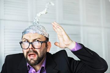 Bearded funny man in a cap of aluminum foil. Concept art phobias.Conspiracy theory. Conspiracy....