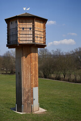 Brown pigeon tower (taubenturm) made of wood. The building stands on a green meadow and serves the animals as a shelter and breeding ground.