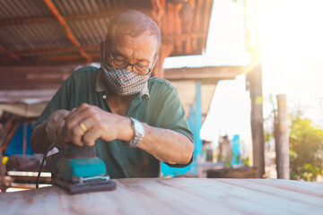 Old man of carpenter working with machine on table