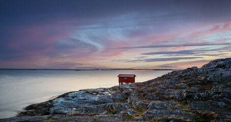 a colorful sunset of a red little fisherman's hut at the coast of sweden. Longe exposure