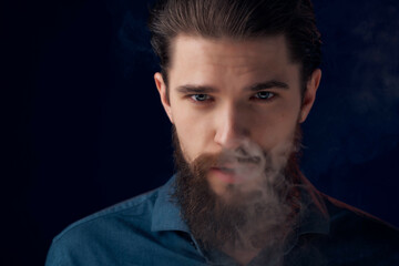 bearded man in a black shirt smoke clouds dark background