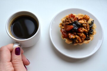 cup of coffee in the female hand and cake