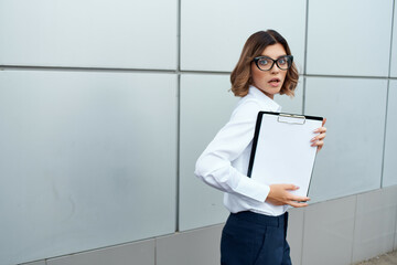 Business woman with documents in hands on the street near the building