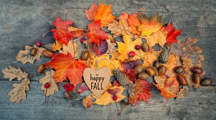 Happy Fall. greeting card and fallen leaves, acorns, cones and paper tag on wooden board. Autumn natural Background. symbol of fall season. flat lay