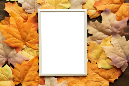 close up top view on mockup white blank paper frame with group of dried orange color maple leaves background texture or autumn season collection design concept