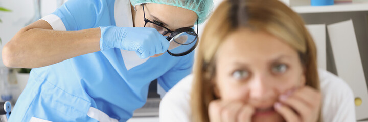 Doctor examining woman rectum with magnifying glass in clinic