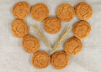 oatmeal cookies laid out in the form of a heart on a beige linen fabric. flat lay