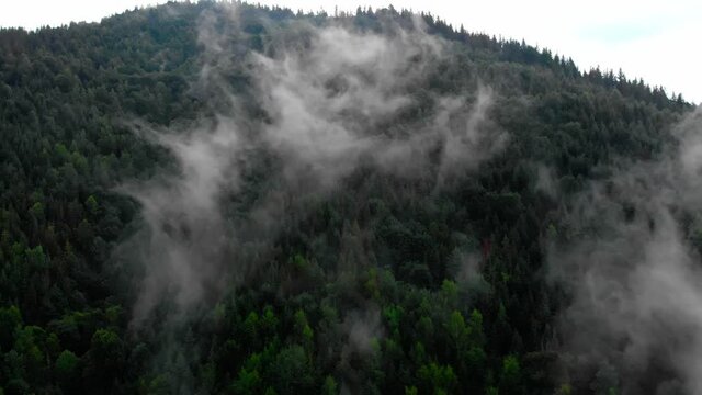 Amazing Aerial View. Flying over the high mountains in beautiful fog . Aerial camera shot. Air clouds. Fog. Steam.