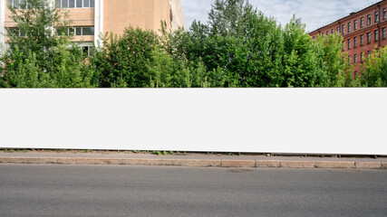 Long huge hoarding with empty space for mockup on street pavement. © Bonsales