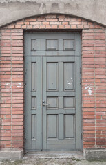 Old gray wooden door in red brick wall, empty abstract interior, vertical background texture