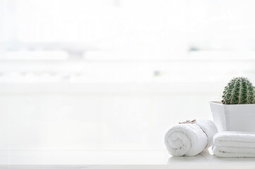 Roll up of white towels on white table with copy space on blurred living room background.