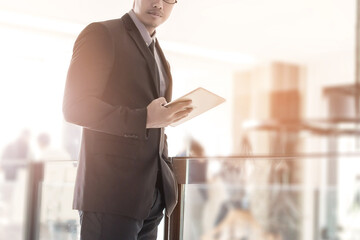 Smart busineesman standing and using tablet for work at office.