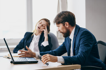 business man and woman sitting at a desk with a laptop communication officials