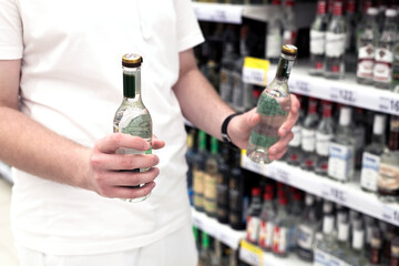 Teenager holding vodka in his hands in interior of the store