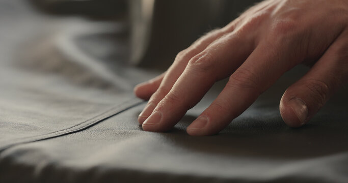 man hand checking soft gray leather clothes