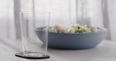Empty tumbler glass on a white oak table with copy space and blue bowl on background