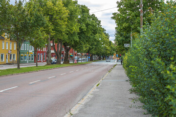Naklejka premium Beautiful city landscape view showing cyclist and cars on road on green trees background. Sweden. Uppsala.
