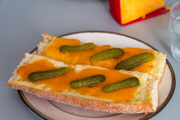 melted cheddar cheese on french bread with gerkin topping ,