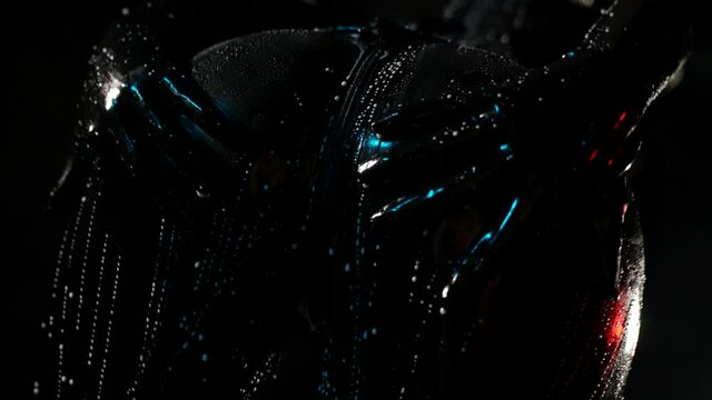 close-up of a female ass in a black latex suit on a dark background. gloved hands smear drops of white liquid