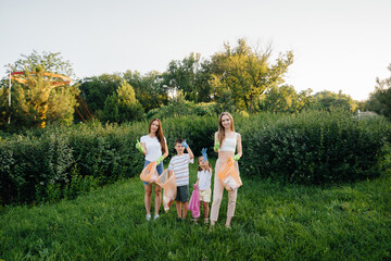 A group of girls with children at sunset are engaged in garbage collection in the park....