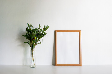 A frame with leaves on a white wall with nature light. 