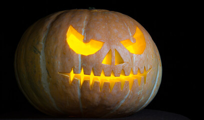 Pumpkin for the Halloween holiday on a black background. A pumpkin on a black background with burning eyes.