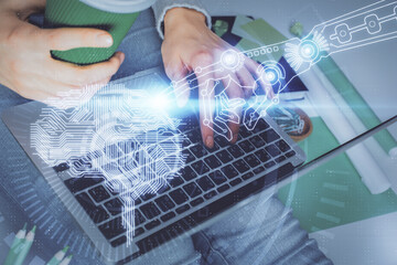 Double exposure of woman hands working on computer and brain hologram drawing. Ai concept.