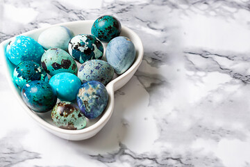 Easter blue quail eggs in a plate in the shape of a heart on a wooden table