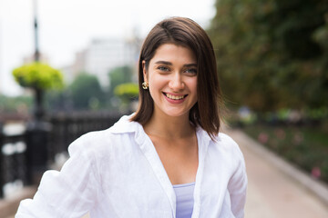 Attractive, happy and stylish brunette Caucasian girl posing on the street. Lifestyle and fashion concept.