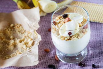 Delicious and healthy yogurt dessert with banana, biscuits and nuts.