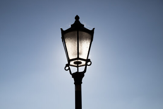 old fashioned streetlamp illuminated by sun in the background